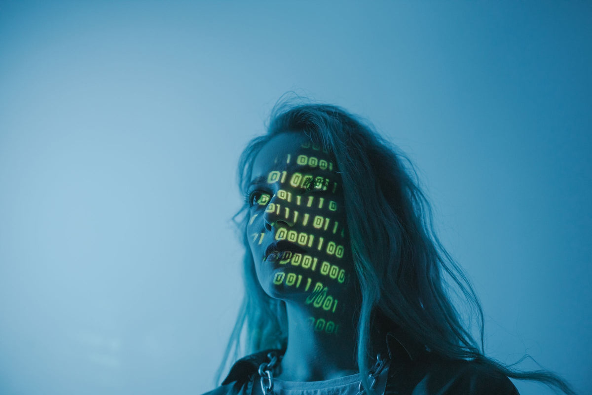 Retrato de una mujer con código digital proyectado en la cara, en luz azul